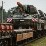 Auf der Schiene an die NATO-Ostflanke: Kampfpanzer, Schützenpanzer und andere Gefechtsfahrzeuge – hier die Panzerhaubitze 2000 – werden oft mit der Bahn in den Einsatzraum transportiert. In Deutschland hauptsächlich durch DB Schenker, das Landtransport auf Straße, auf der Schiene oder in einer Kombination aus beidem bietet.