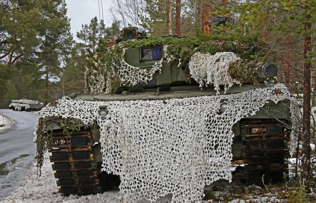Kampfpanzer Leopard 2A4NO des norwegischen Heeres verblendet mit weißen und grünen Tarnnetzen.