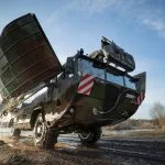 Eine Amphibie M3, der Vorgänger der neuen Schwimmschnellbrücke 2, verlässt das Gewässer und klappt ihre Seitenschwimmkörper wieder ein.