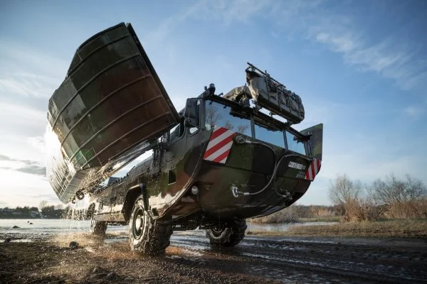 Eine Amphibie M3, der Vorgänger der neuen Schwimmschnellbrücke 2, verlässt das Gewässer und klappt ihre Seitenschwimmkörper wieder ein.