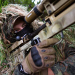 Ein KSK-Soldat der Bundeswehr bei der Scharfschützenausbildung interessiert sich auch für das KSK Symposium..