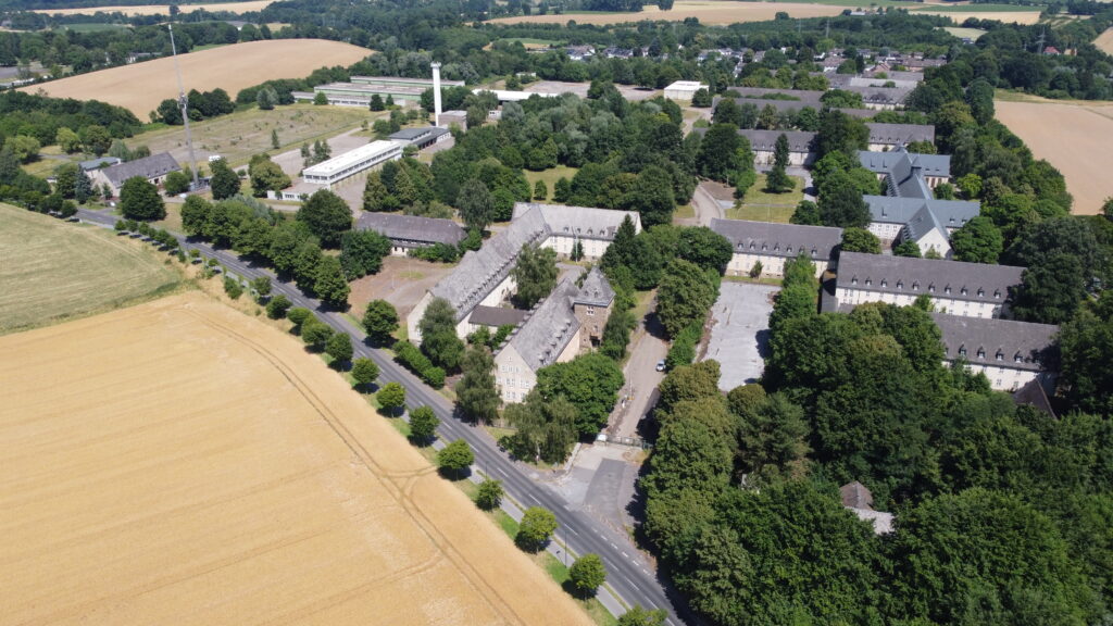 Luftbild der Bergischen Kaserne. Alle Gebäude auf der rechten Bildseite, sowie das Stabsgebäude in der unteren Bildmitte sind denkmalgeschützt. Im linksseitigen Hintergrund erkennt man die Gerätehallen.