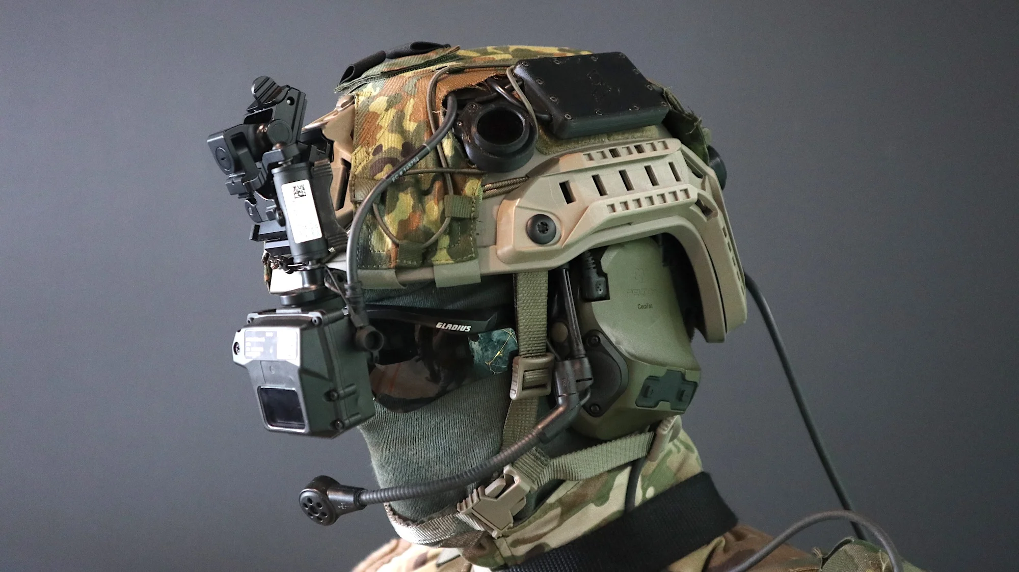 Der "Infanterist der Zukunft" trägt eine Menge digitaler Unterstützung: Um den Gefechtshelm mit Tarnbezug finden sich ein aktiver Gehörschutz samt Mikrofon, Laser-Warngerät und ein Head-up-Display THEA von THEON.