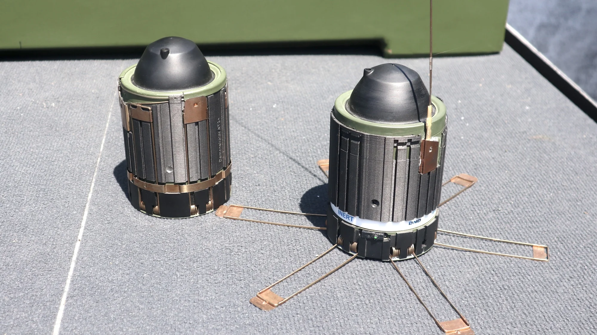 Die Panzerabwehrmine AT2+ von DND – rechts mit aufgesprungenen Bügeln, die nach dem Abwurf für eine aufrechte Position sorgen.