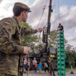 Wackliges Bauwerk: Am Klettergurt gesichert arbeitet sich ein Junge geschickt Kasten für Kasten in die Höhe.