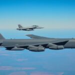 B-52 Bomber wird von Kampfjet begleitet.